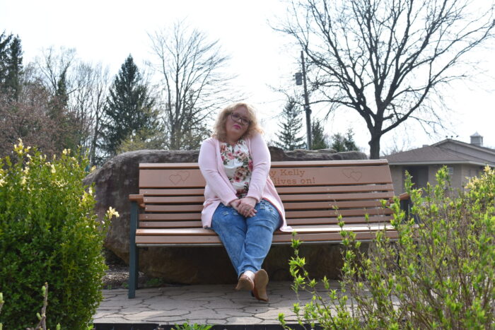 person in pink cardigan, jeans, and floral shirt looking in deep thought