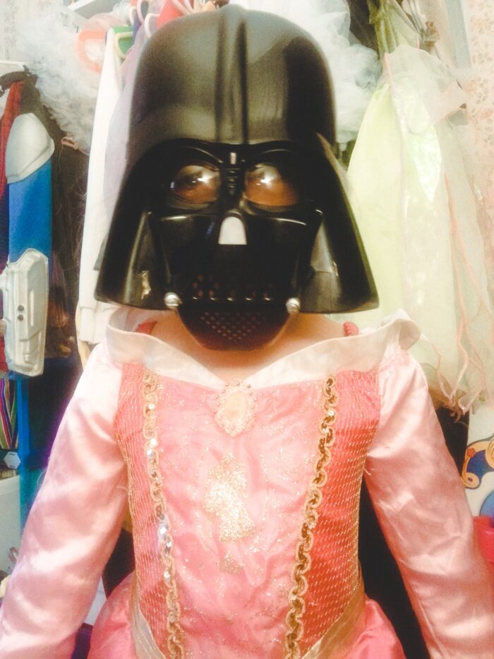 child wearing pink dress and Darth Vader Mask