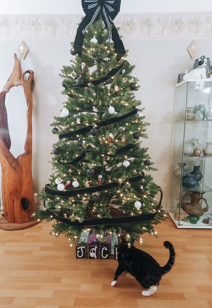 Cat checking out King Of Christmas 7.5' Yorkshire Fir Artificial Christmas Tree with Nightmare Before Christmas decor