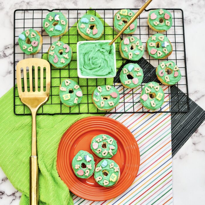 St. Patrick's Day Air Fryer Lucky Charms Donuts on a tray and a plate with a spatula
